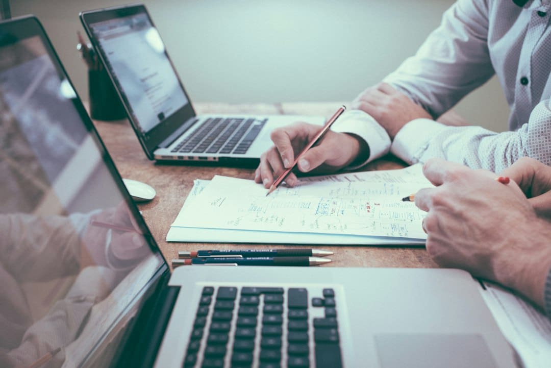 Personas trabajando en laptops y documentos administrativos.
